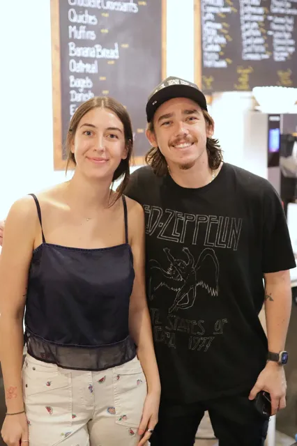 Young couple smiling together inside a cafe, with a chalkboard menu in the background