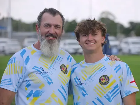 Father and son pose together on the rugby field in matching Commonwealth Globetrotters jerseys